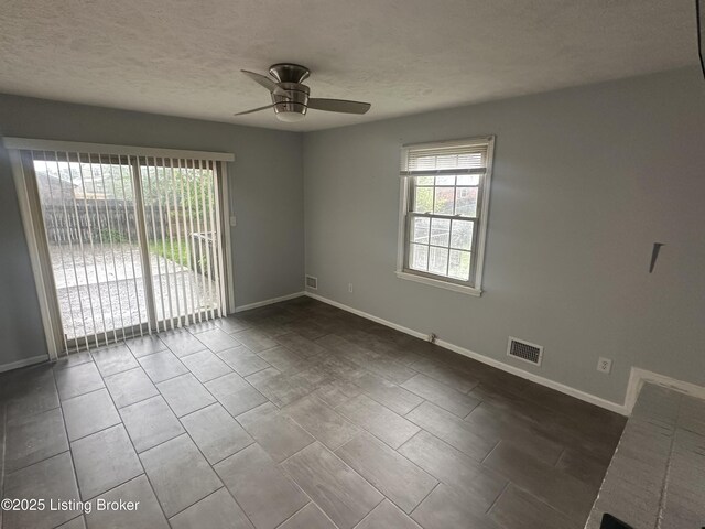 unfurnished room with baseboards, visible vents, a ceiling fan, and a textured ceiling