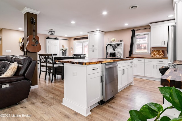 kitchen featuring a sink, butcher block countertops, a barn door, appliances with stainless steel finishes, and open floor plan