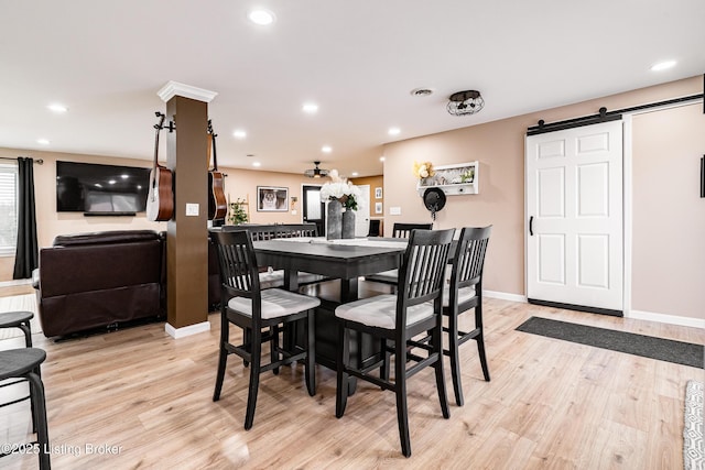 dining area featuring recessed lighting, baseboards, a barn door, and light wood-style floors