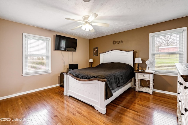 bedroom featuring multiple windows, ceiling fan, hardwood / wood-style flooring, and baseboards