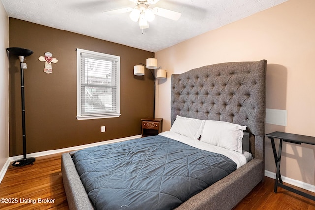 bedroom featuring baseboards, wood finished floors, and a ceiling fan