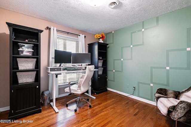 home office with baseboards, visible vents, wood finished floors, and a textured ceiling