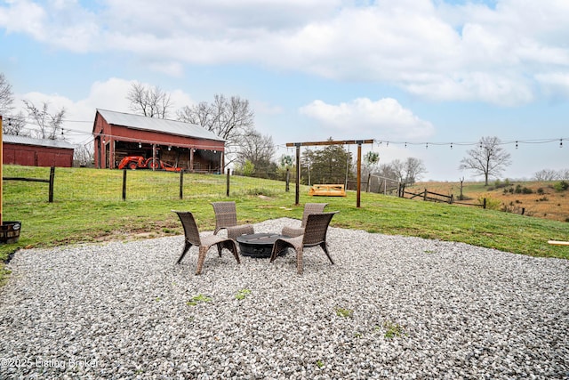 view of patio / terrace with a pole building, a fire pit, an outbuilding, and fence