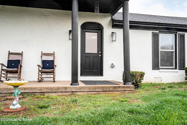 property entrance featuring brick siding and a lawn