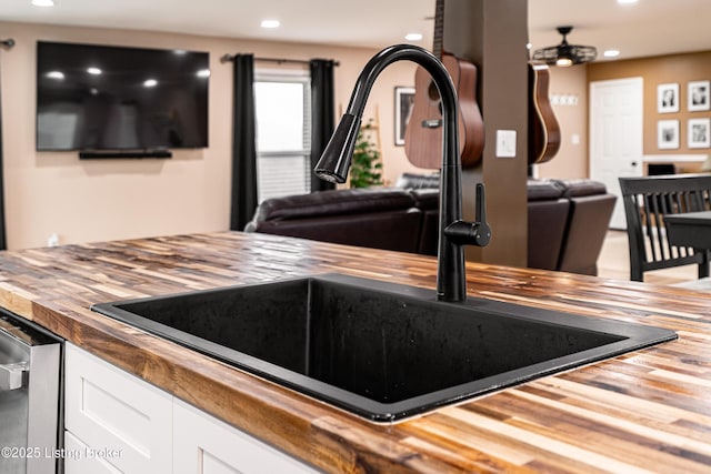 interior details featuring recessed lighting, stainless steel dishwasher, butcher block countertops, white cabinets, and a sink
