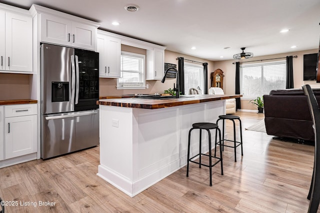 kitchen with white cabinetry, plenty of natural light, stainless steel fridge with ice dispenser, and butcher block counters