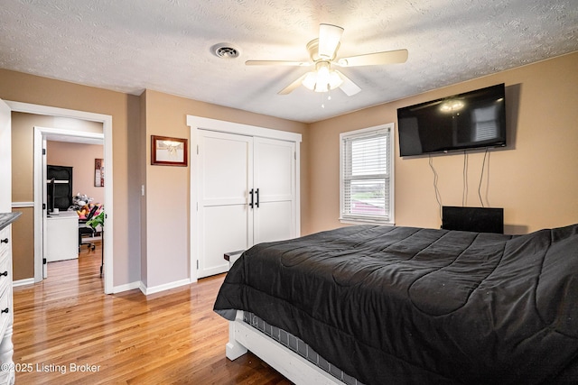 bedroom featuring a closet, ceiling fan, baseboards, light wood-type flooring, and a textured ceiling