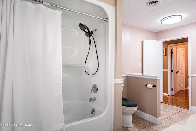 bathroom with tile patterned floors, shower / bath combo with shower curtain, toilet, visible vents, and a textured ceiling