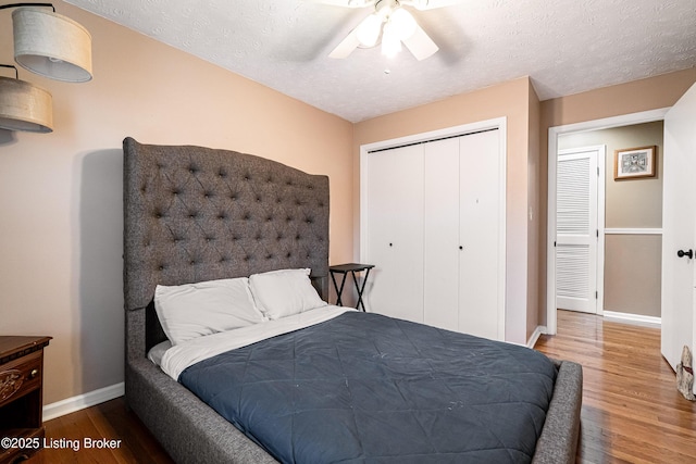 bedroom featuring a closet, a ceiling fan, baseboards, a textured ceiling, and wood finished floors
