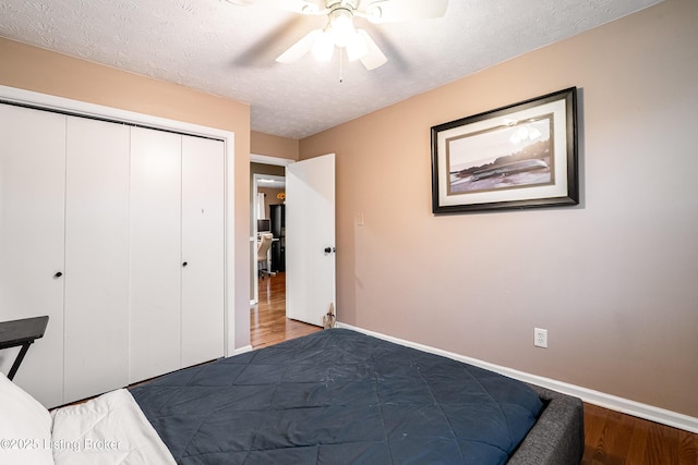 bedroom featuring baseboards, wood finished floors, a textured ceiling, and a closet