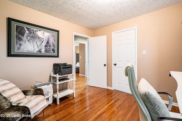 office area featuring baseboards, wood finished floors, and a textured ceiling