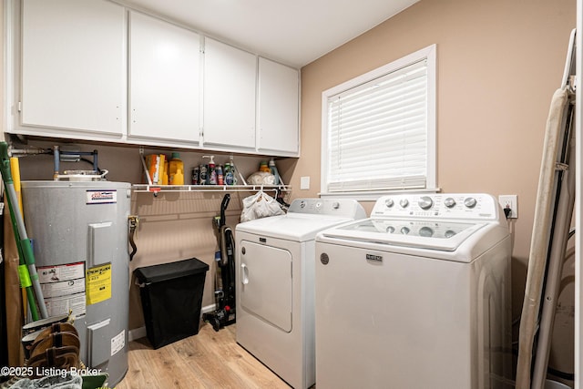 laundry area with cabinet space, water heater, light wood finished floors, and washing machine and dryer