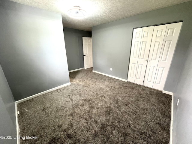 unfurnished bedroom featuring baseboards, a textured ceiling, a closet, and carpet