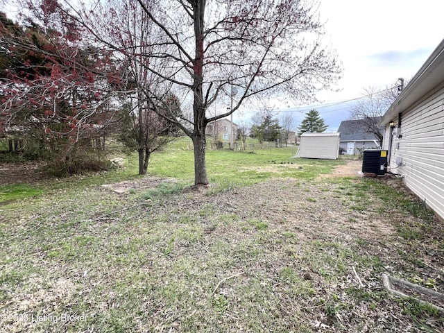 view of yard featuring a shed, an outbuilding, and central air condition unit