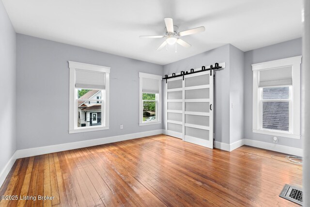 415 Gwendolyn St, Louisville, KY 40203 - spare room with a barn door, baseboards, wood-type flooring, and a ceiling fan