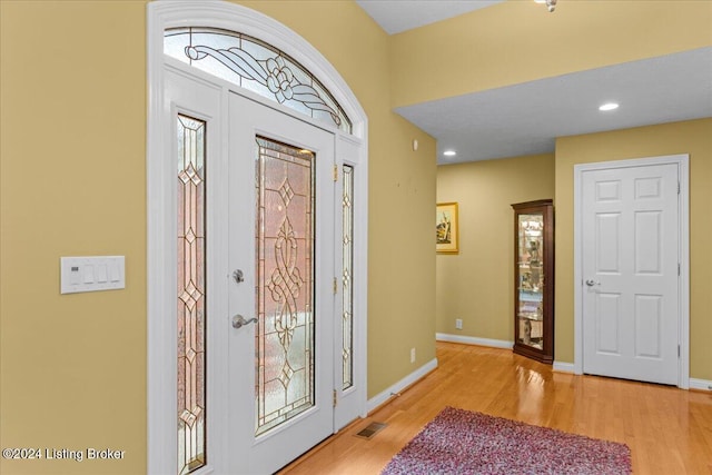 foyer featuring baseboards, visible vents, and wood finished floors