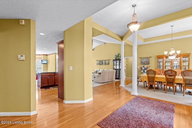 dining space featuring a chandelier, light wood finished floors, and decorative columns