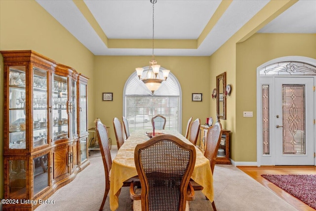 dining room featuring a raised ceiling, a chandelier, and baseboards