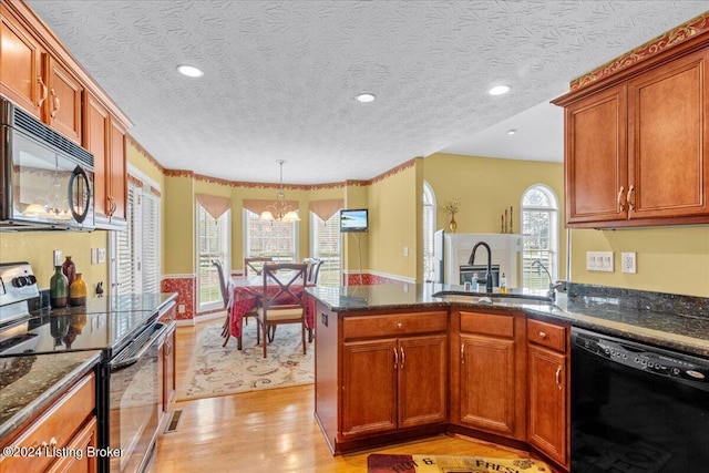 kitchen with a chandelier, light wood-style floors, black appliances, a sink, and a peninsula