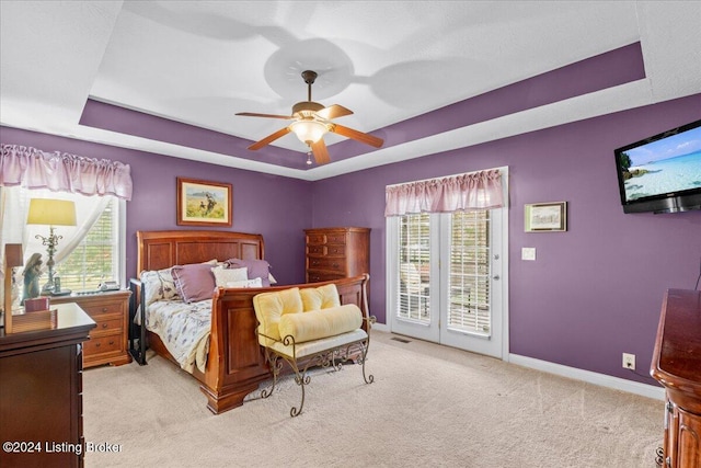 bedroom featuring ceiling fan, a raised ceiling, access to exterior, light carpet, and baseboards
