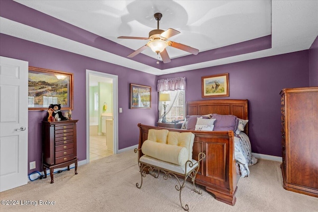 bedroom featuring a raised ceiling, a ceiling fan, baseboards, carpet floors, and ensuite bathroom