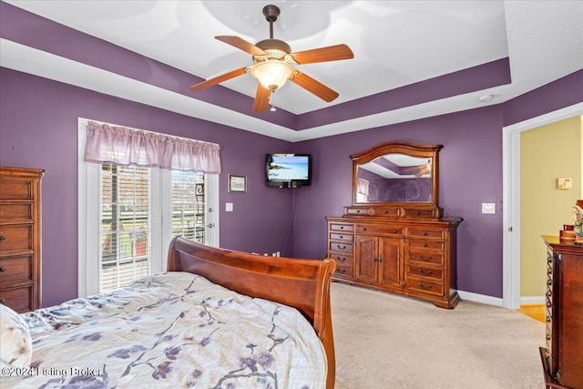 bedroom with ceiling fan, a raised ceiling, access to exterior, light carpet, and baseboards