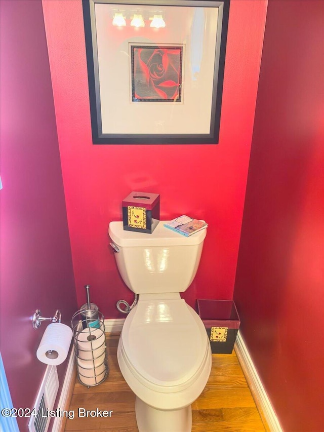 bathroom with wood finished floors, toilet, and baseboards