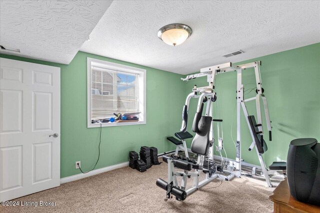 exercise room featuring carpet floors, a textured ceiling, visible vents, and baseboards