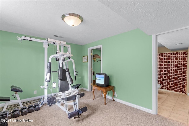 workout room featuring a textured ceiling, visible vents, carpet, and baseboards