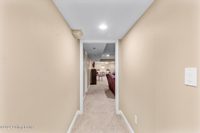 corridor featuring baseboards and light colored carpet