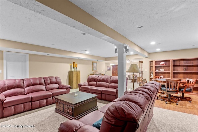 carpeted living area featuring recessed lighting, wood finished floors, ornate columns, and a textured ceiling