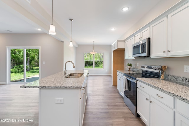 1332 Etawah Ave, Louisville, KY 40222 - kitchen featuring appliances with stainless steel finishes, a sink, light wood-style flooring, white cabinetry, and a kitchen island with sink