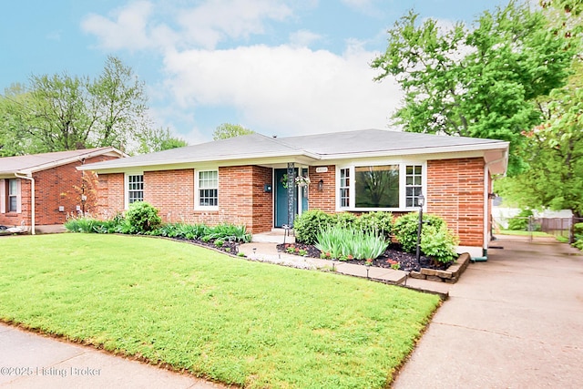 single story home featuring driveway, a front yard, and brick siding