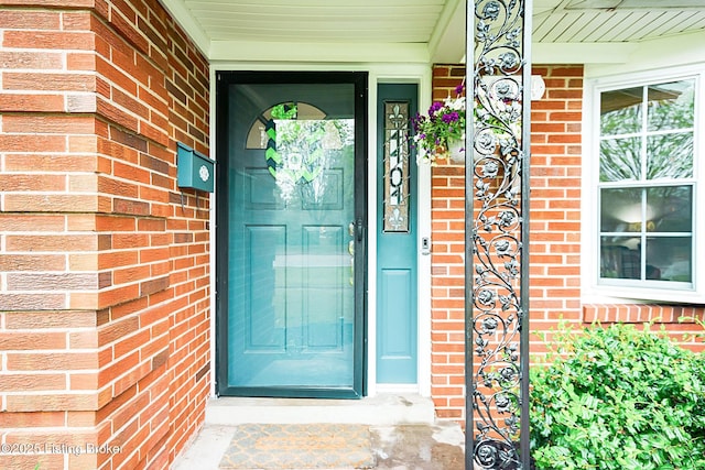 doorway to property featuring a porch and brick siding