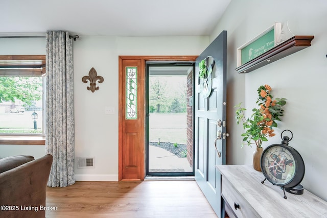 entrance foyer with light wood finished floors, visible vents, a wealth of natural light, and baseboards