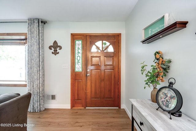 foyer featuring baseboards, visible vents, light wood finished floors, and plenty of natural light