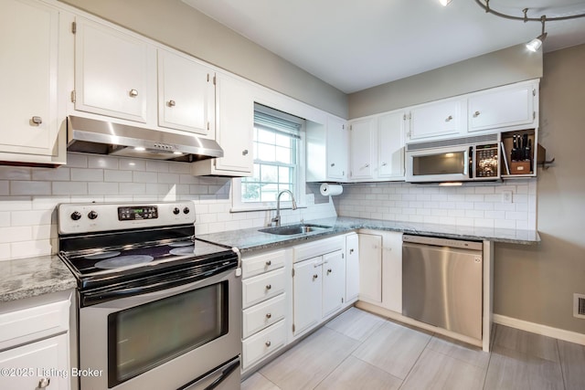 kitchen with light stone countertops, a sink, under cabinet range hood, white cabinets, and appliances with stainless steel finishes