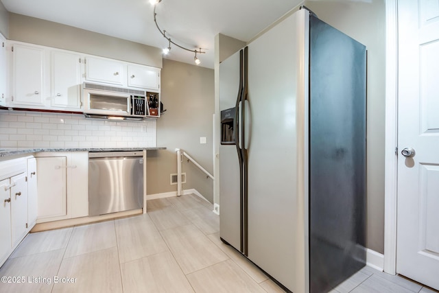 kitchen with white cabinets, tasteful backsplash, appliances with stainless steel finishes, and baseboards