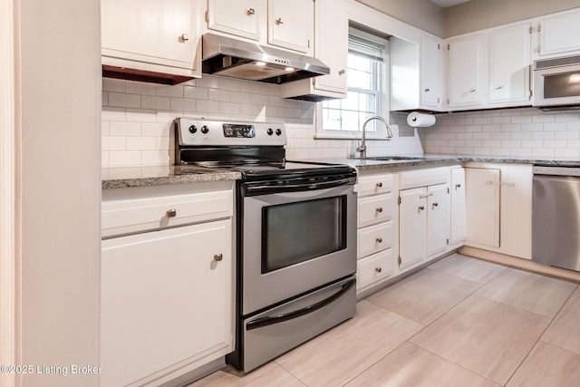 kitchen featuring tasteful backsplash, appliances with stainless steel finishes, under cabinet range hood, white cabinets, and a sink