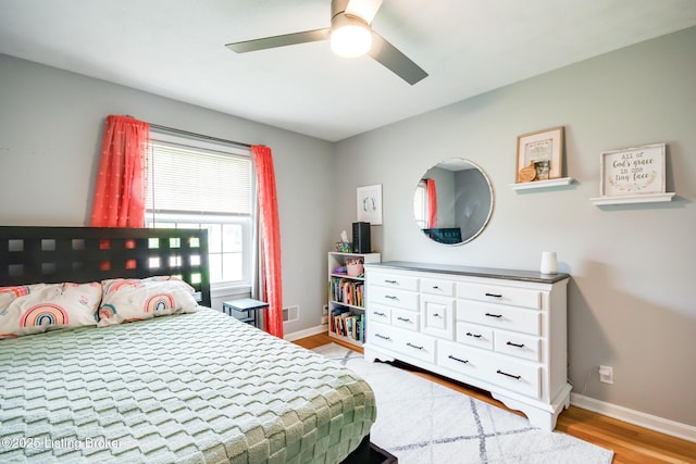 bedroom with baseboards, light wood-type flooring, visible vents, and ceiling fan