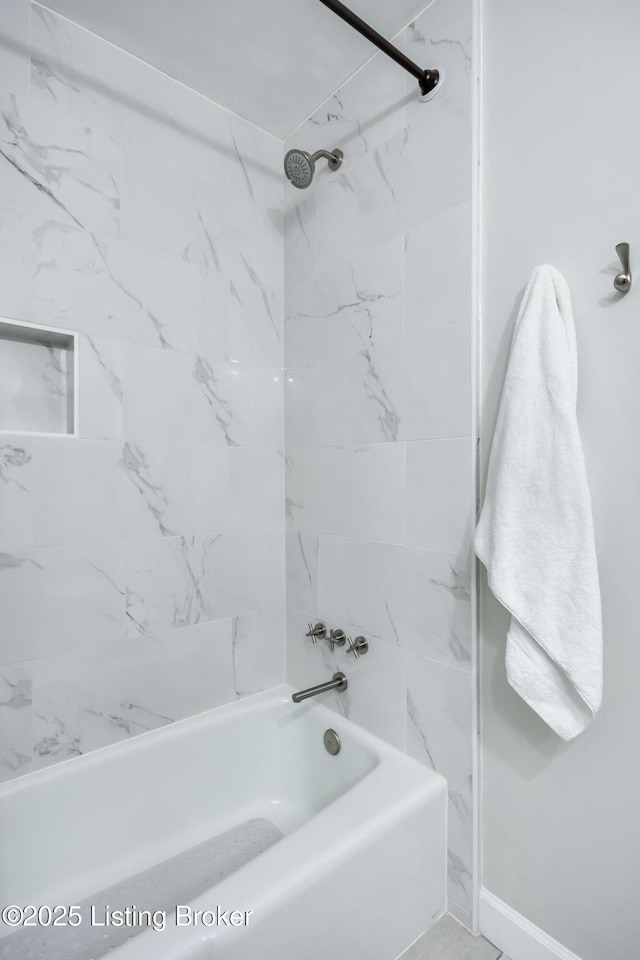 bathroom with bathing tub / shower combination and baseboards