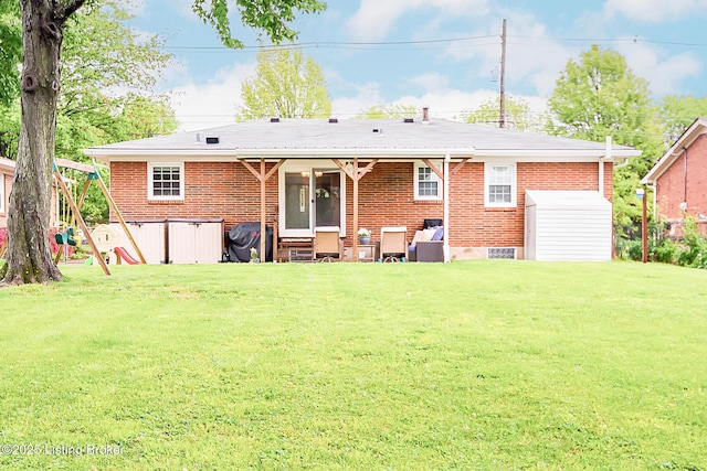 back of house featuring brick siding and a yard
