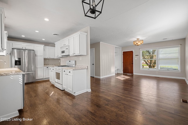 kitchen with a notable chandelier, white appliances, dark wood-type flooring, baseboards, and open floor plan