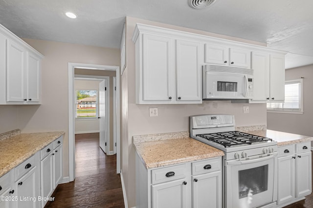 kitchen featuring white cabinetry, visible vents, white appliances, and a wealth of natural light