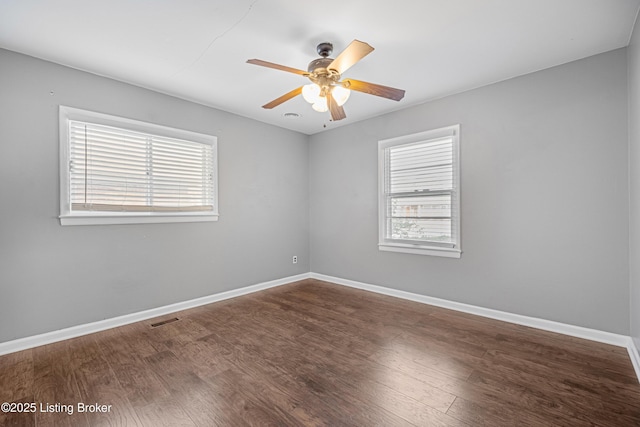 spare room featuring visible vents, wood finished floors, a wealth of natural light, and a ceiling fan
