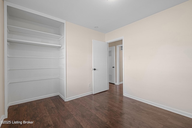 unfurnished bedroom with baseboards, wood finished floors, and a closet