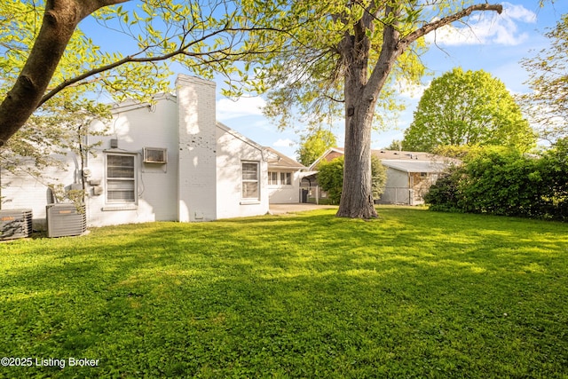 view of yard with central AC and fence