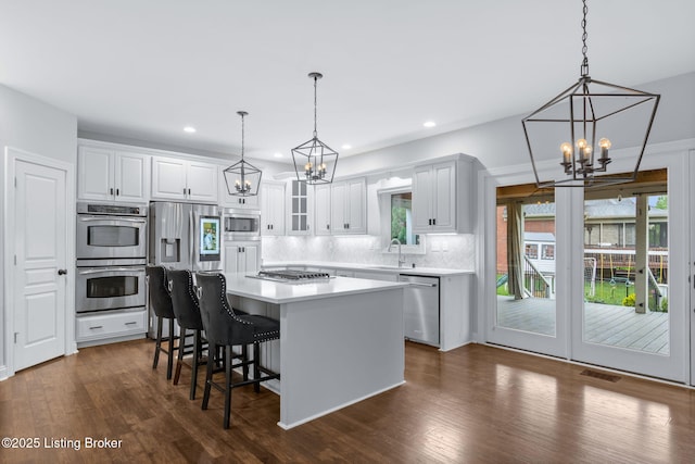 kitchen with decorative backsplash, appliances with stainless steel finishes, a center island, a sink, and a chandelier