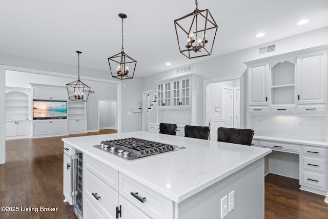 kitchen featuring stainless steel gas cooktop, a notable chandelier, dark wood-style floors, and visible vents