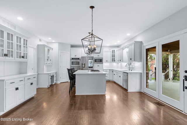 kitchen with visible vents, a center island, a sink, a notable chandelier, and stainless steel appliances